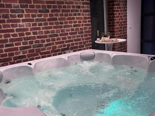 Cette chambre dispose d'un bain à remous et d'un mur en briques. dans l'établissement Gîte Familial au Cœur des Flandres avec Cheminée et Grand Jardin - FR-1-510-16, à Oudezeele