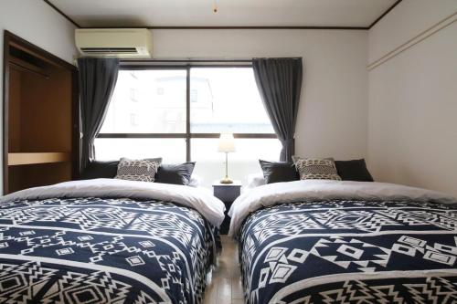 a bedroom with two beds and a window at ラフィーネハイツ201 in Fuchu