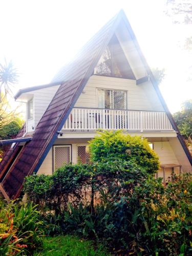 a house with a gambrel roof with a porch at Family or Friends Cottage in North Tamborine