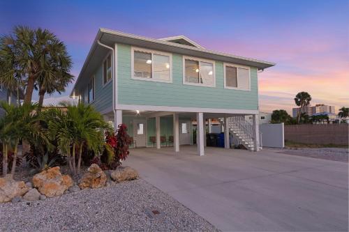ein grünes Haus mit einer Einfahrt und Palmen in der Unterkunft Amber Jack - 210 Ostego Dr home in Fort Myers Beach