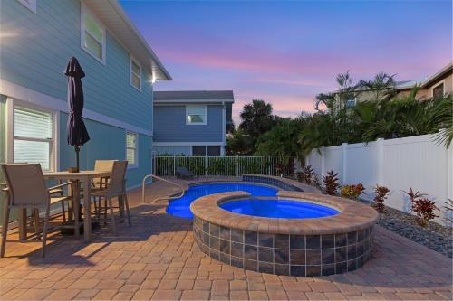 eine Terrasse mit einem Pool, einem Tisch und Stühlen in der Unterkunft Amber Jack - 210 Ostego Dr home in Fort Myers Beach