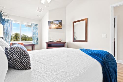 a white bedroom with a bed and a mirror at Cape Crossing 106 in Merritt Island