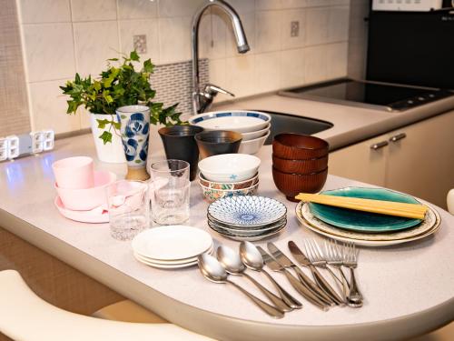 eine Küchentheke mit Tellern und Küchenutensilien darauf in der Unterkunft The Global West in Niihama