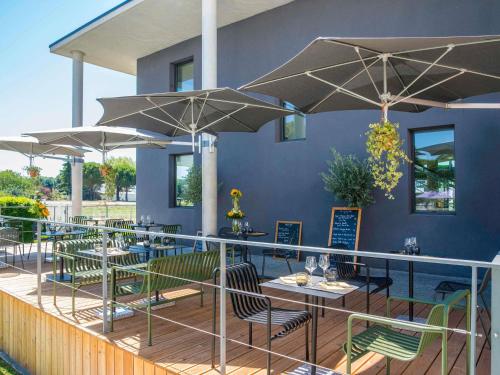a restaurant with tables and umbrellas on a deck at ibis Styles Pertuis Portes du Luberon in Pertuis