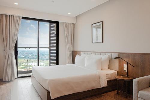 a bedroom with a large bed and a large window at Mandala Hotel & Suites Hải Dương in Bảo Thap