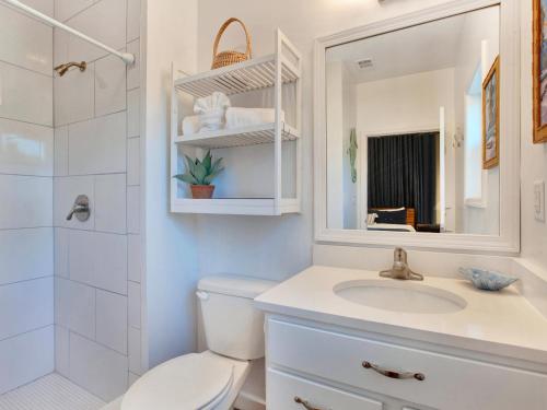 Un baño con inodoro, lavabo y espejo. en Lime Time, en Tybee Island