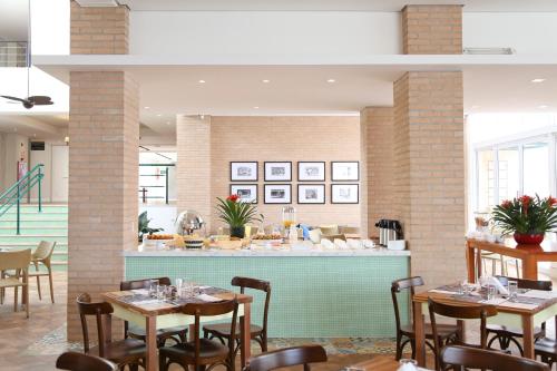 a restaurant with tables and chairs and a bar at Vitória Hotel Express Dom Pedro in Campinas