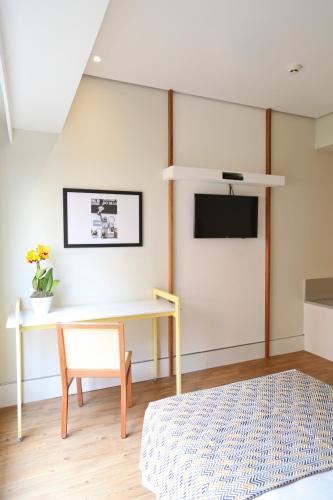 a room with a table and a tv on a wall at Vitória Hotel Express Dom Pedro in Campinas