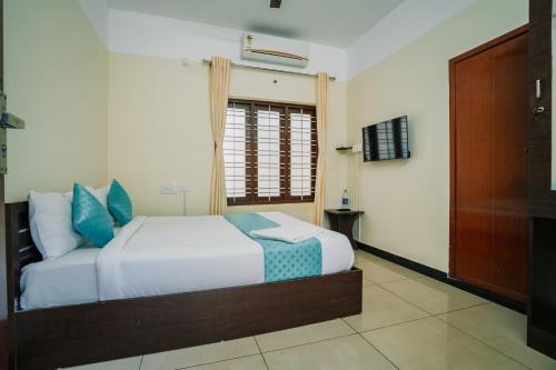 a bedroom with a white bed with blue pillows at Infinity Rooms Kazhakkoottam Technopark in Trivandrum