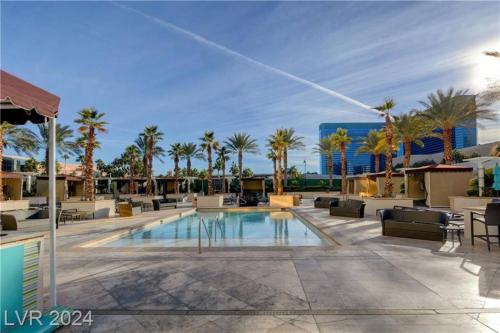 a pool with chaise lounge chairs and palm trees at The Condos at MGM Signature Hotel in Las Vegas