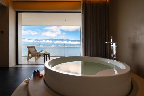 a bathroom with a large tub in front of a window at Dali Rushi Jiuxi Sea View Holiday Inn in Dali Airport