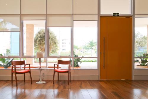 a room with chairs and a table and windows at Vitória Hotel Express Dom Pedro in Campinas
