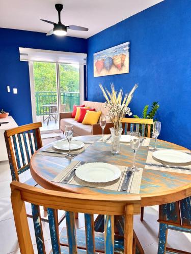 a dining room with a table with chairs and a blue wall at NOVIDADE! Apartamento Bella Vita Bertioga in Bertioga