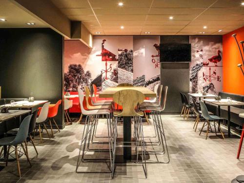 a dining room with tables and chairs and paintings on the walls at Ibis Saint-Genis-Pouilly Genève in Saint-Genis-Pouilly
