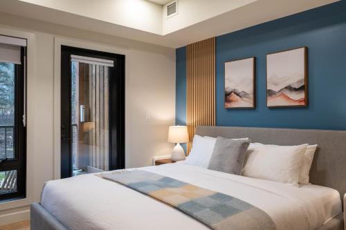 een slaapkamer met een groot bed met blauwe muren bij Brand New Canmore Studio - Cozy Mountain Getaway in Canmore
