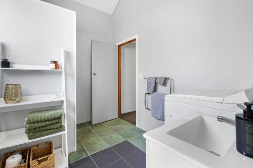 Un baño blanco con lavabo y espejo. en Self-contained Studio close to Kensington Park, en Whangarei