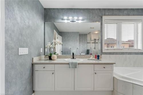 ein Badezimmer mit Waschbecken und großem Spiegel in der Unterkunft Tranquil Haven near Niagara in Thorold