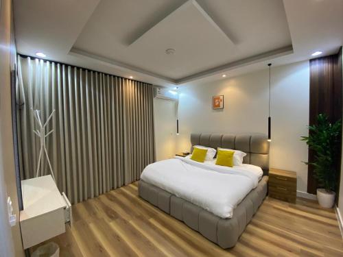 ein Schlafzimmer mit einem großen weißen Bett mit gelben Kissen in der Unterkunft Hala 12B - شقة فاخرة بغرفة وصالة in Quai