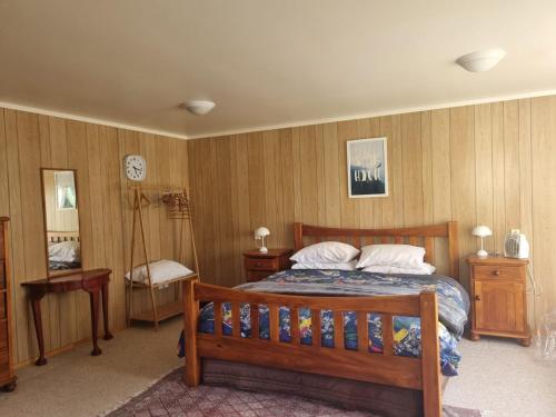 a bedroom with a bed and wooden walls at Hosts on the Coast Family Times in Whitianga