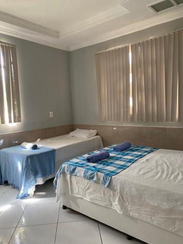 a bedroom with two beds and a table in it at Vivenda Hotel in Arapiraca