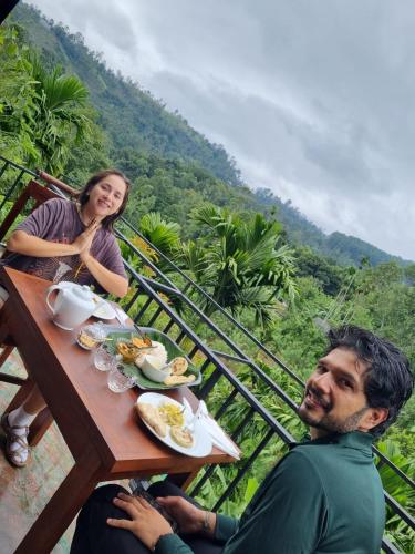 um homem e uma mulher sentados à mesa com comida em New Arch Heaven Ella em Ella