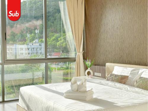 a bedroom with a white bed with a large window at Modern Haven Suite in Hat Yai in Ban Thung Ngai