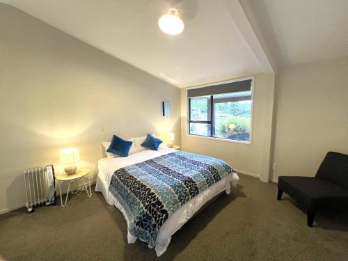 une chambre avec un lit avec des oreillers bleus et une fenêtre dans l'établissement Mt Aspiring Holiday Park, à Wanaka