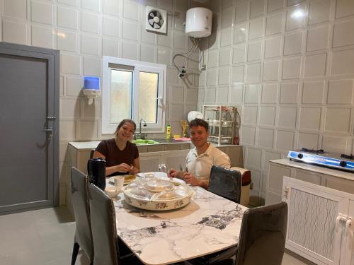 um homem e uma mulher sentados numa mesa numa cozinha em SLASEL JABAL SHAMS HOUsE em Sa‘ab Banī Khamīs