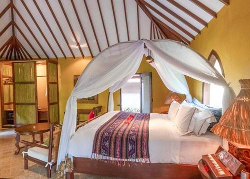 丹戎Hotel Tugu Lombok的卧室里有一张带顶篷的大床