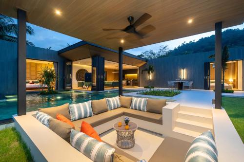 an outdoor living room with a couch and a ceiling fan at Cocoon Villa 5 - Luxurious 3BR Pool Retreat near Naithon Beach in Nai Thon Beach
