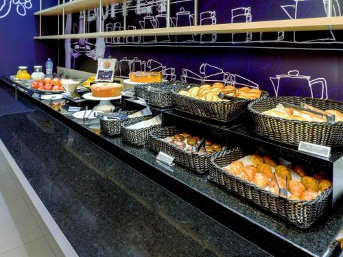 uma linha de buffet com cestas de pão e outros alimentos em ibis budget Osasco em Osasco