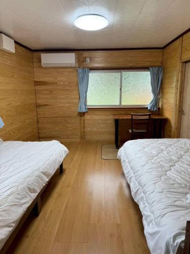 a bedroom with two beds and a table and a window at Seasid830 in Kuranomoto