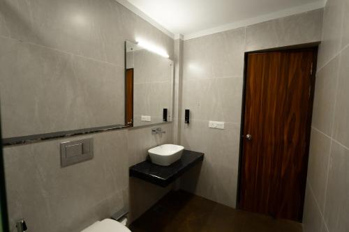 Un baño con lavabo, espejo e inodoro. en Hotel White Flower, en Jāmb