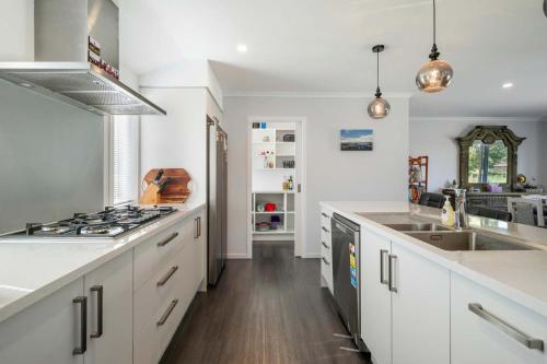 une cuisine avec des comptoirs blancs et une cuisinière dans l'établissement Hamurana Hotspot - Walk to the Lake & Golf Course, à Hamurana