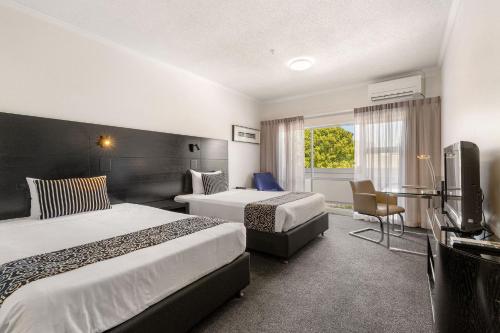 a hotel room with two beds and a television at Hotel Armitage and Conference Centre in Tauranga