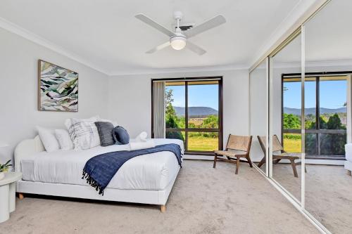 ein weißes Schlafzimmer mit einem Bett und einem großen Fenster in der Unterkunft Helena Grand Estate Hunter Valley in Ellalong