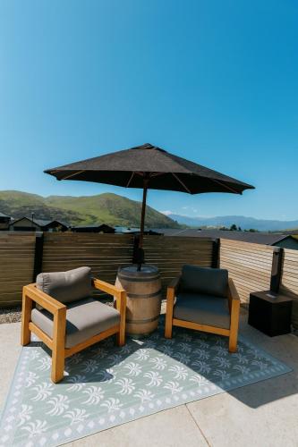 a patio with two chairs and an umbrella at Queenstown Studio with Mountain Views in Frankton