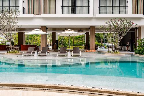 a hotel swimming pool with chairs and umbrellas at Laya Resort -Tropical Studio in Layan Beach