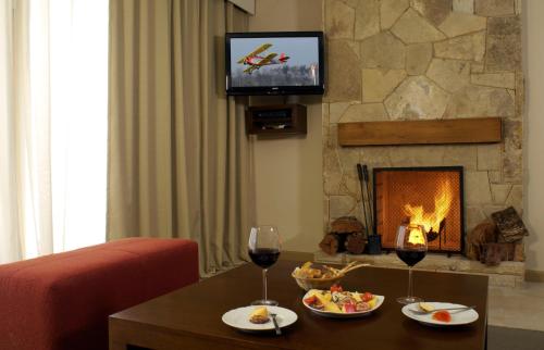 a living room with a fireplace and two glasses of wine at Village Condo in San Carlos de Bariloche