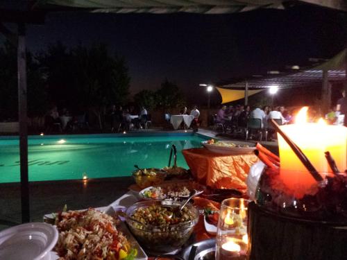 a table with food next to a swimming pool at night at Pausania Inn in Tempio Pausania