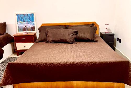 een slaapkamer met een groot bed met twee nachtkastjes bij Refúgio Urbano in Jacareí