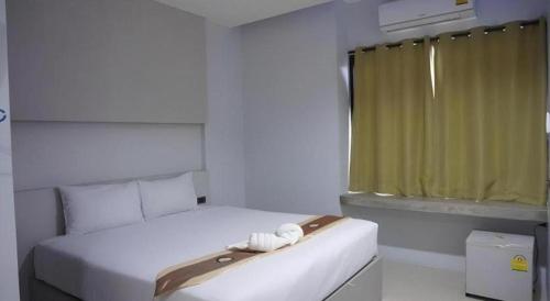 a bedroom with a white bed with a green curtain at C2U Hotel Uthai Thani in Ban Khok Mo