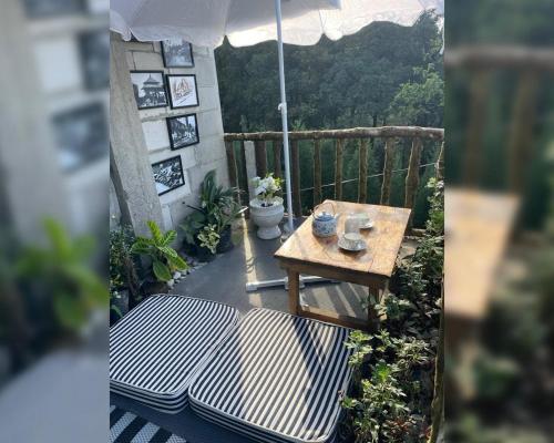 une table de pique-nique sur un balcon avec un parasol dans l'établissement Lee's Grandma's Will Cottage, à Kalimpong