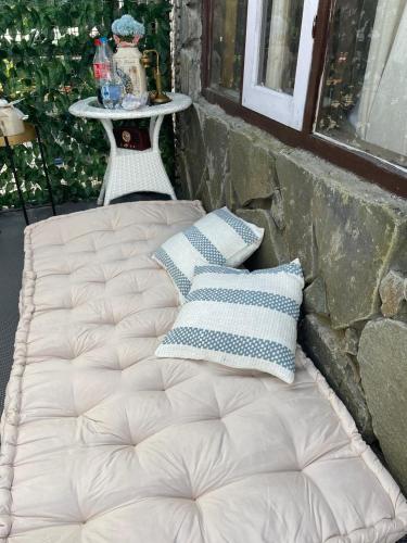 un lit adossé à un mur de pierre avec des oreillers dans l'établissement Lee's Grandma's Will Cottage, à Kalimpong