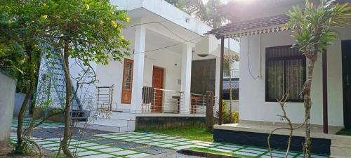 une maison blanche dotée d'une terrasse couverte et d'escaliers. dans l'établissement Munroe Heritage Inn, à Munroe Island