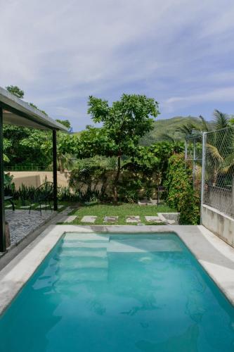 a swimming pool with blue water in a yard at Villa Palmarcito in El Zonte