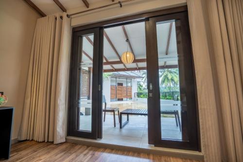 une porte coulissante en verre menant à une terrasse avec une table. dans l'établissement Lavendish Beach Resort, à Unawatuna