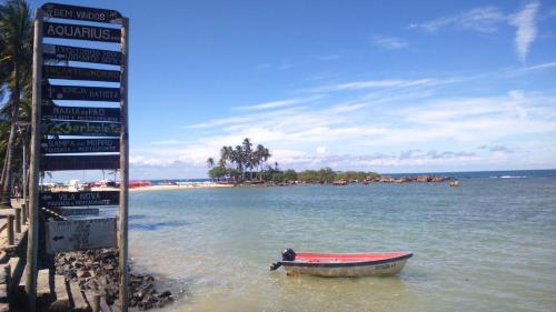 a small boat in the water next to a sign at Pousada Borboleta in Morro de São Paulo