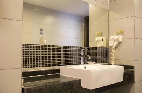 ein Badezimmer mit einem weißen Waschbecken und einem Spiegel in der Unterkunft Borrman Hotel Liuzhou Ma'anshan Park Gubu Shopping Mall in Liuzhou