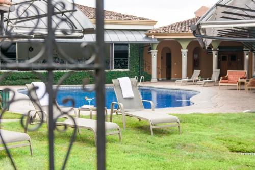 a yard with chairs and a pool in a house at Casa Conde Hotel & Apartamentos in San José